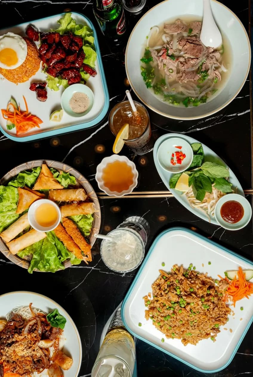 Table dressée avec nems, phở et accompagnements